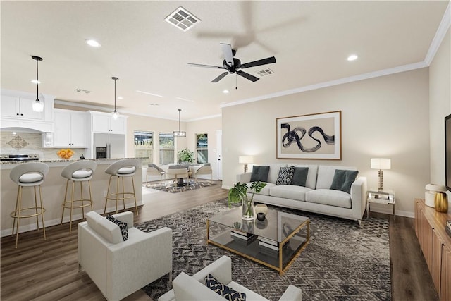 living room with dark hardwood / wood-style flooring, ceiling fan, and crown molding