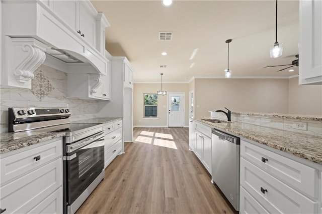 kitchen featuring light wood-type flooring, stainless steel appliances, white cabinetry, and hanging light fixtures