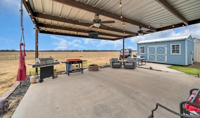 view of patio with a rural view, a storage shed, a grill, and ceiling fan