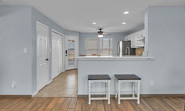 kitchen featuring ceiling fan, white cabinetry, stainless steel appliances, light hardwood / wood-style floors, and kitchen peninsula