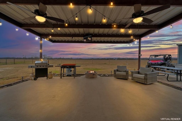 patio terrace at dusk featuring area for grilling, a rural view, and an outdoor fire pit