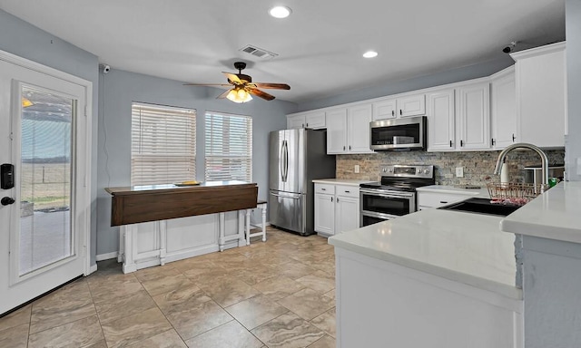 kitchen with sink, white cabinetry, ceiling fan, stainless steel appliances, and backsplash