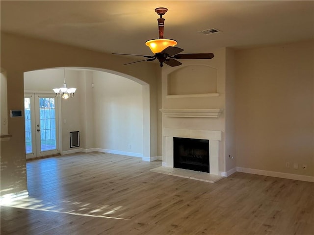 unfurnished living room with a fireplace, ceiling fan with notable chandelier, and hardwood / wood-style flooring