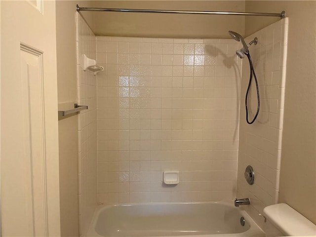 bathroom featuring tiled shower / bath combo and toilet