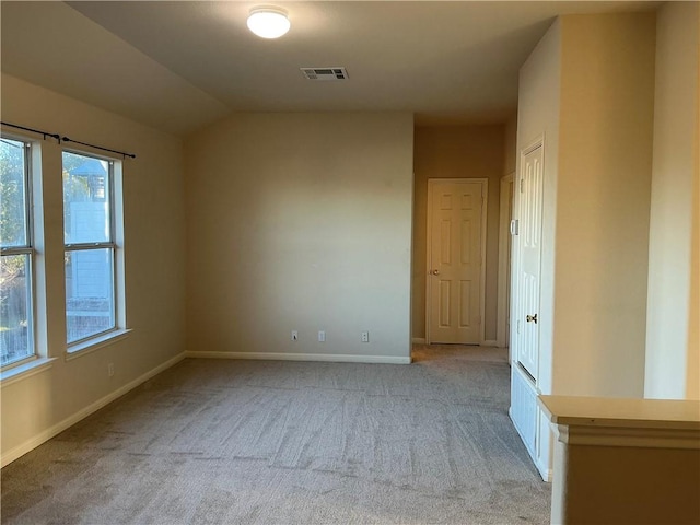 spare room with light carpet, lofted ceiling, and a healthy amount of sunlight