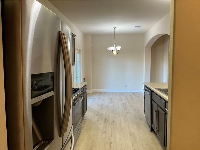 kitchen featuring appliances with stainless steel finishes, sink, an inviting chandelier, light hardwood / wood-style floors, and hanging light fixtures