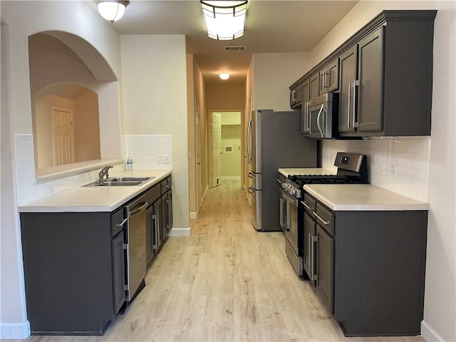 kitchen with backsplash, sink, light hardwood / wood-style flooring, dark brown cabinetry, and stainless steel appliances