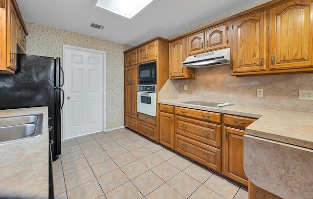 kitchen featuring backsplash, light tile patterned floors, sink, and black appliances