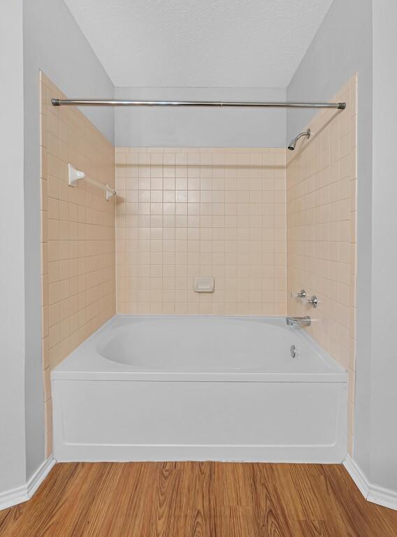 bathroom with tiled shower / bath, wood-type flooring, and a textured ceiling