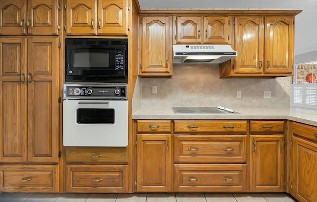 kitchen with light tile patterned floors, black microwave, tasteful backsplash, electric stovetop, and oven