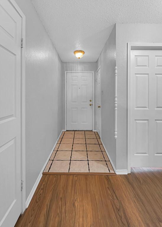 hall with a textured ceiling and light wood-type flooring