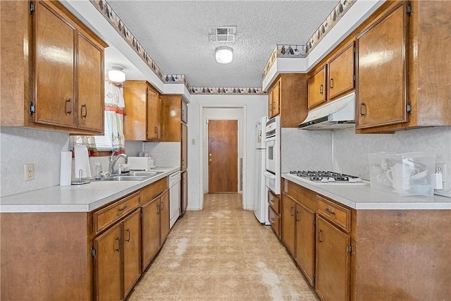 kitchen with a textured ceiling, sink, and white appliances