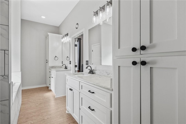 bathroom with wood-type flooring, vanity, and a bathtub