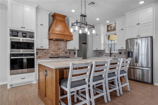 kitchen with stainless steel fridge, white cabinetry, a kitchen island, and custom exhaust hood