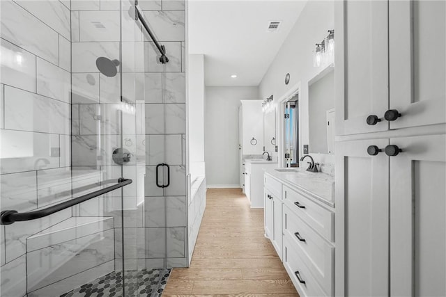 bathroom featuring hardwood / wood-style floors, vanity, and plus walk in shower