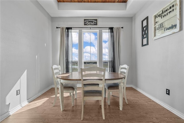 dining area featuring hardwood / wood-style flooring, wooden ceiling, and a tray ceiling