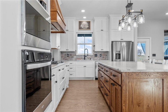 kitchen featuring appliances with stainless steel finishes, backsplash, sink, white cabinets, and a center island