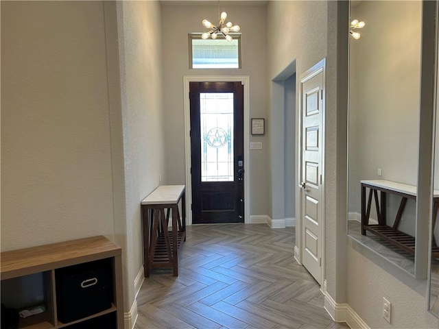 entrance foyer with a chandelier, a towering ceiling, and light parquet floors