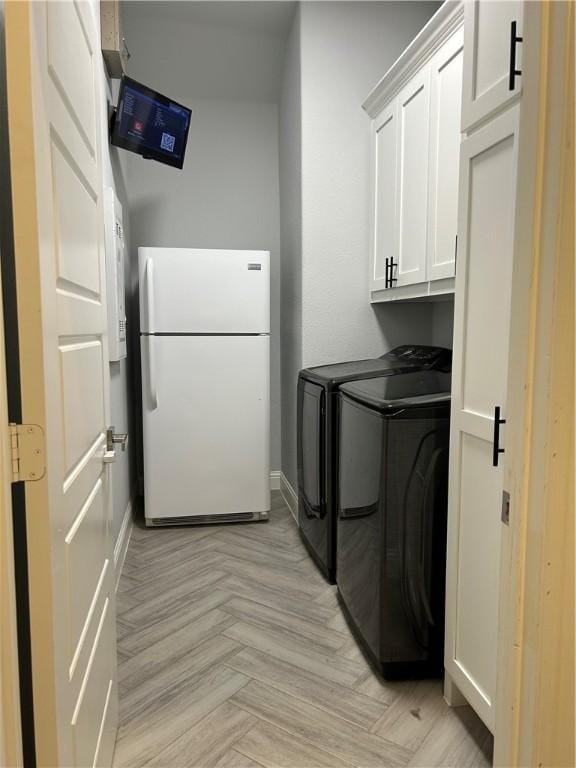 laundry area featuring washer and dryer, light parquet floors, and cabinets