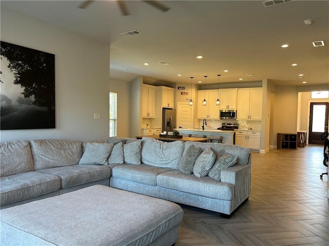 living room with a healthy amount of sunlight, sink, and light parquet flooring