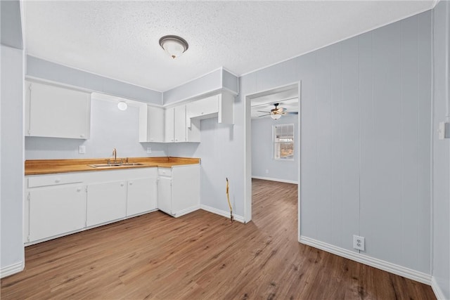 kitchen with white cabinets, light hardwood / wood-style floors, butcher block countertops, and sink