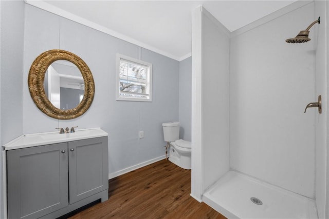 bathroom with ornamental molding, vanity, a shower, hardwood / wood-style floors, and toilet