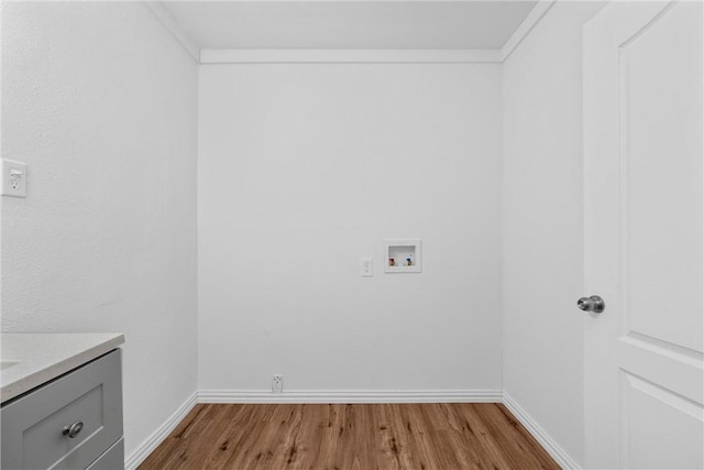 laundry area featuring crown molding, hookup for a washing machine, cabinets, and light hardwood / wood-style flooring