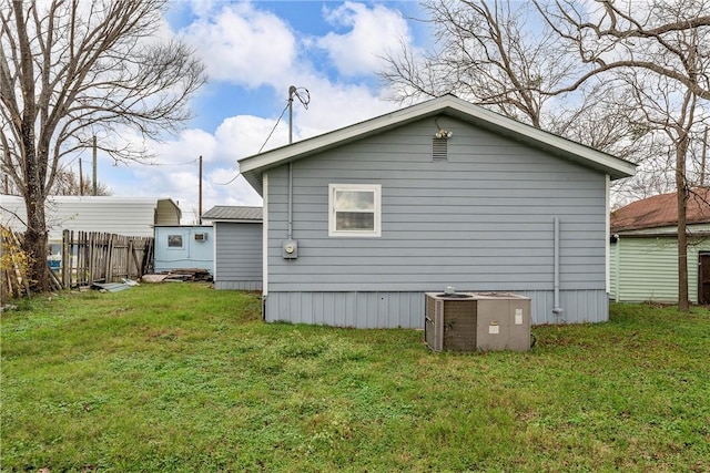 view of side of property featuring central AC unit and a lawn