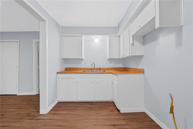 kitchen with white cabinetry, sink, and light hardwood / wood-style flooring