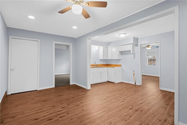 unfurnished living room featuring light hardwood / wood-style floors, ceiling fan, and sink