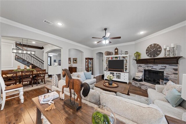 living room featuring a fireplace, crown molding, dark hardwood / wood-style flooring, and ceiling fan