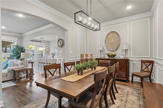 dining space with a notable chandelier, wood-type flooring, and ornamental molding