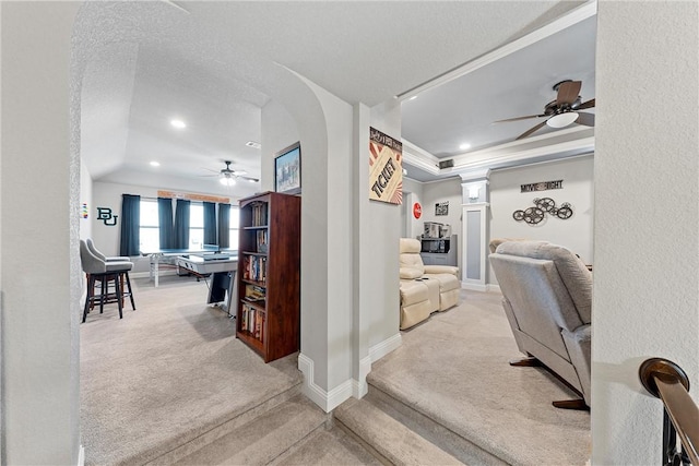 hallway with a textured ceiling, light colored carpet, and ornate columns