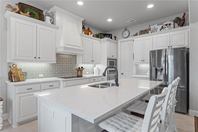 kitchen with white cabinetry, an island with sink, and stainless steel appliances