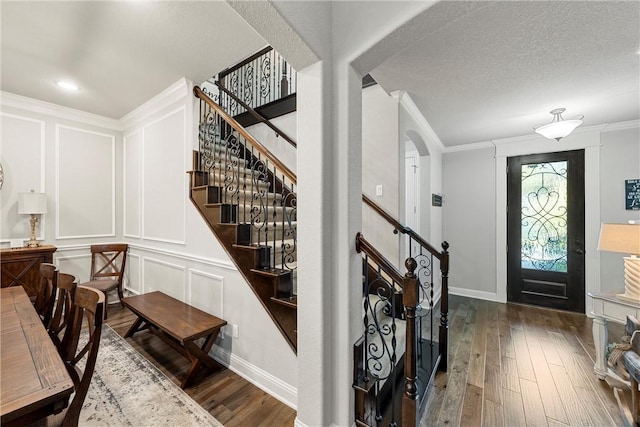 foyer entrance with dark hardwood / wood-style flooring, a textured ceiling, and ornamental molding