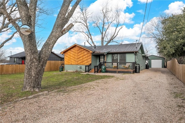 view of front of house with a garage, a front yard, and an outbuilding