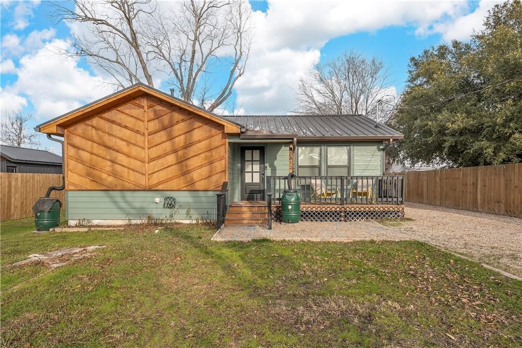 back of house with a wooden deck and a lawn