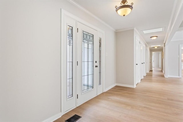 foyer featuring light wood-type flooring, baseboards, visible vents, and ornamental molding