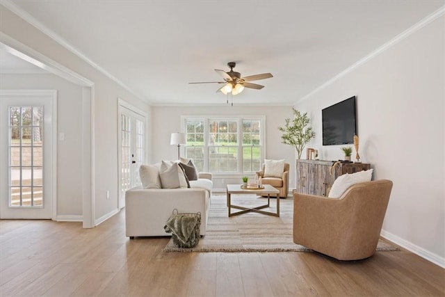 living area with ornamental molding, wood finished floors, and a healthy amount of sunlight