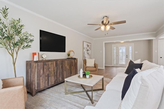 living room with ornamental molding, ceiling fan, baseboards, and wood finished floors