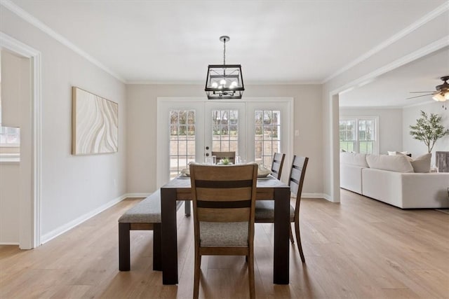 dining room with light wood-style floors, crown molding, baseboards, and ceiling fan with notable chandelier