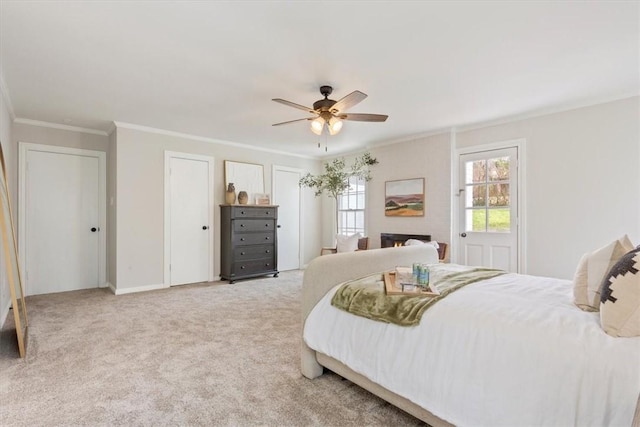 carpeted bedroom featuring ceiling fan, a fireplace, baseboards, multiple closets, and ornamental molding