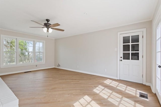 empty room featuring ornamental molding, visible vents, light wood-style flooring, and baseboards