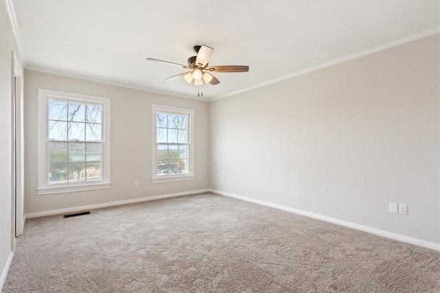 empty room with baseboards, visible vents, a ceiling fan, crown molding, and carpet flooring