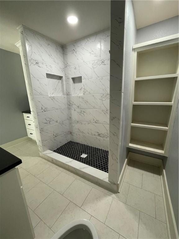 bathroom with tiled shower and vanity