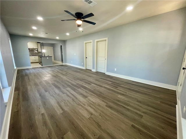 unfurnished living room with ceiling fan, dark hardwood / wood-style flooring, and sink