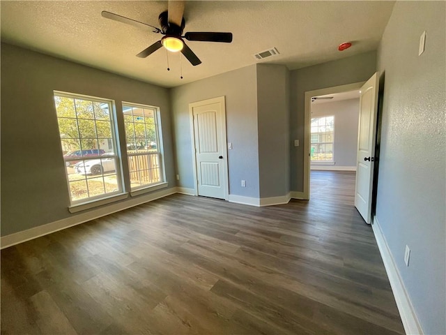 unfurnished bedroom with multiple windows, ceiling fan, and dark hardwood / wood-style floors