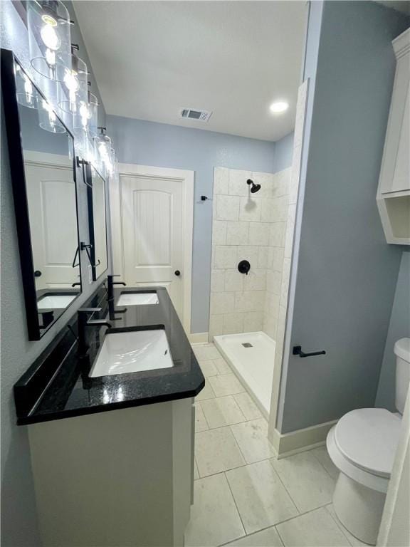 bathroom featuring tile patterned flooring, toilet, vanity, and tiled shower