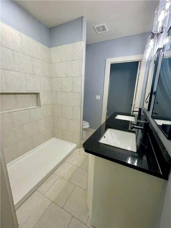 bathroom with a shower, tile patterned floors, vanity, and toilet