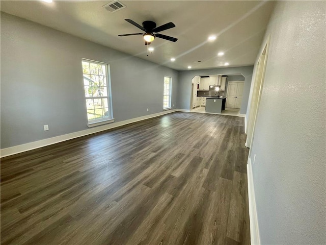 unfurnished living room featuring a wealth of natural light, dark hardwood / wood-style flooring, and ceiling fan